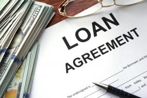 Loan agreement on a table and dollars.