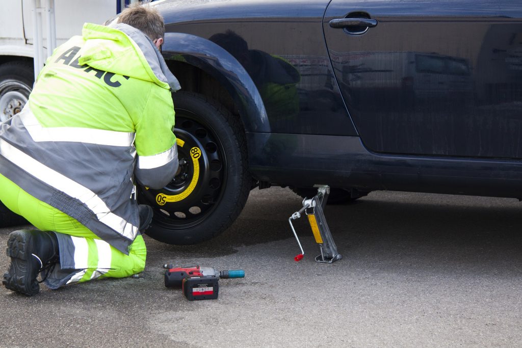 mechanic attending to flat tire of car - fast cash loans